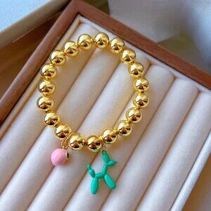 Copper bracelets plated in 18-karat gold with enameled peach and dog charms